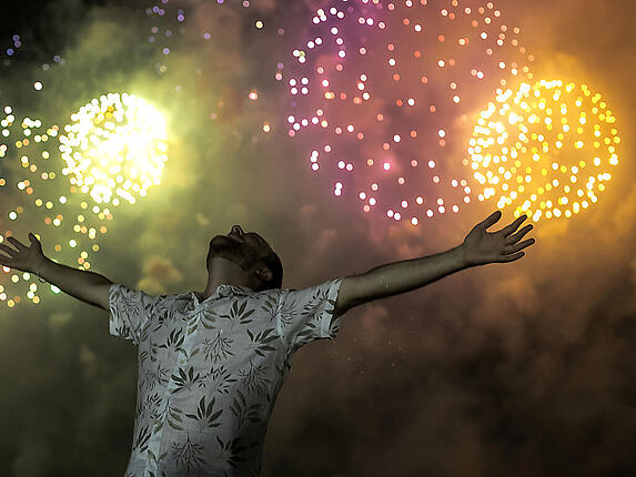 dpatopbilder - Ein Mann feiert den Beginn des neuen Jahres, während im Hintergrund ein Feuerwerk über dem Copacabana-Strand in Rio De Janeiro den Nachthimmel erleuchtet. Foto: Bruna Prado/AP/dpa