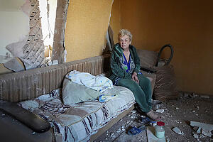 Eine ukrainische Frau sitzt in ihrer Wohnung in einem Gebäude, das bei einem Raketenangriff  zerstört wurde. Foto: Andrii Marienko/AP/dpa