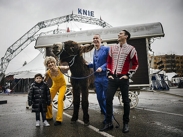 "Zugpferde" der Knie Tournee 2022: Ursus & Nadeschkin, Bastian Baker (rechts) und Maycol Knie junior posieren mit Esel Ferdinand vor dem Zirkuszelt in Rapperswil.
