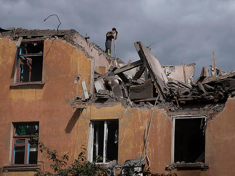 Ein Feuerwehrmann steht auf dem Dach eines Hauses in Slowjansk, das durch Beschuss des russischen Militärs schwer beschädigt wurde. Foto: Leo Correa/AP/dpa