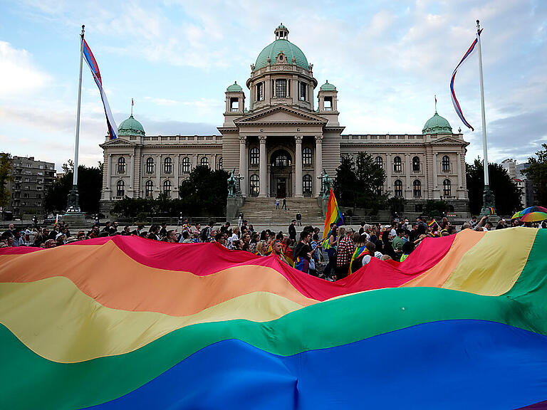 ARCHIV - Teilnehmerinnen und Teilnehmer tragen im September 2021 eine große Regenbogenfahne vor dem Parlamentsgebäude, während des jährlichen LGBTQ-Pride-Marsches. Foto: Darko Vojinovic/AP/dpa/Archiv